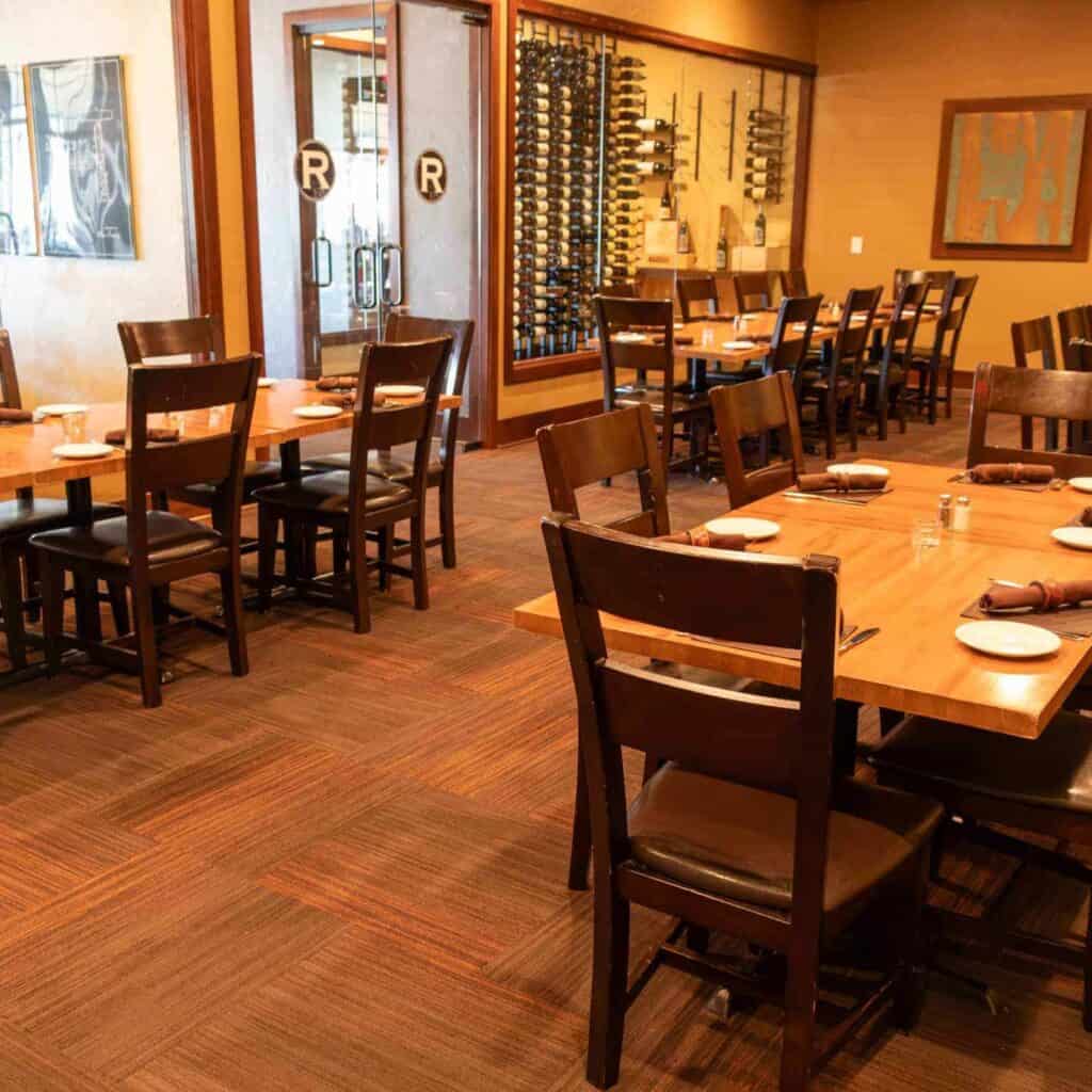 Empty restaurant dining area with wooden tables and chairs.